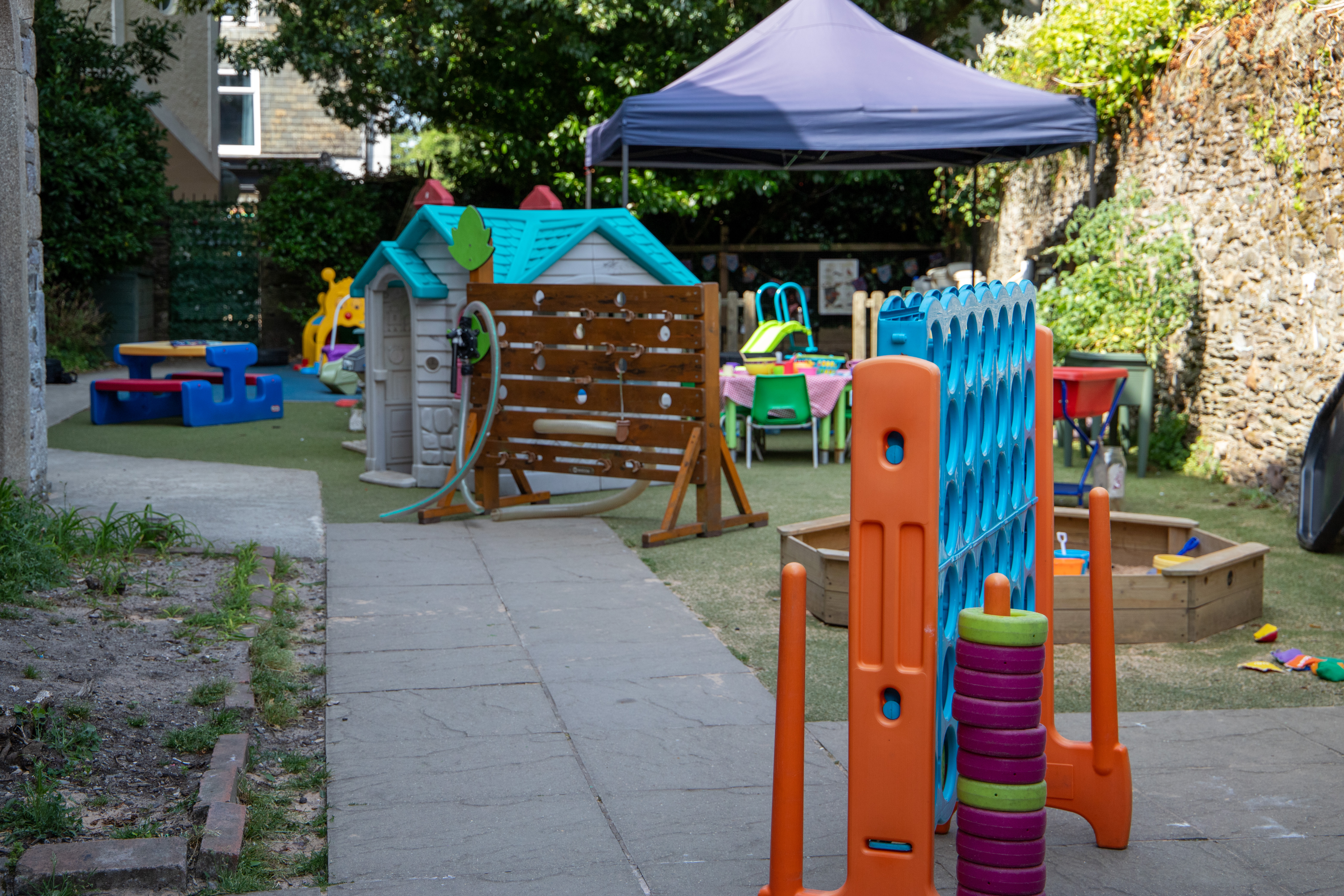 The outdoor play area — playhouse, water wall, sandpit and giant games on the all-weather surface